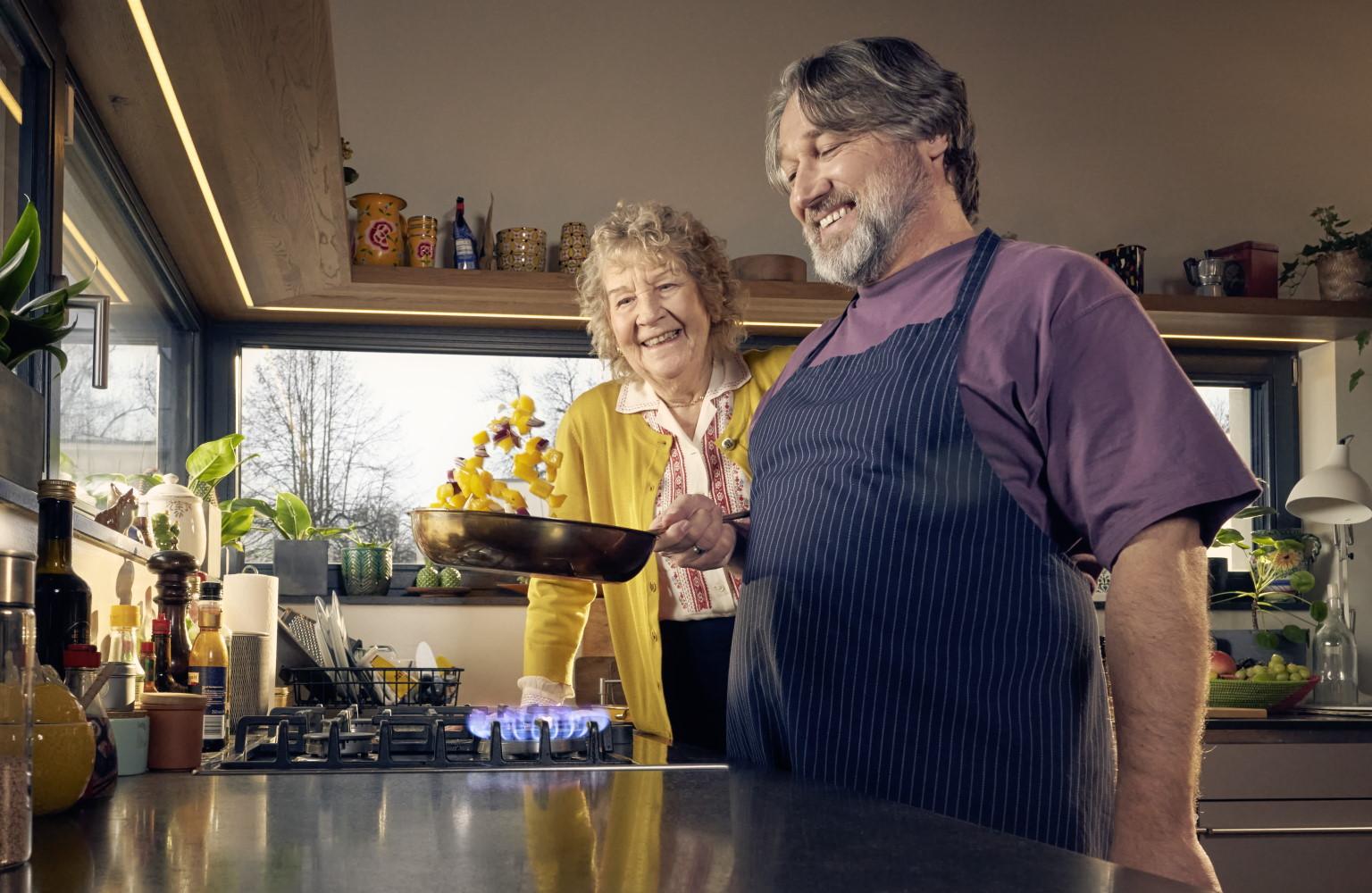 Mann und ältere Dame kochen in einer Küche am Gasherd