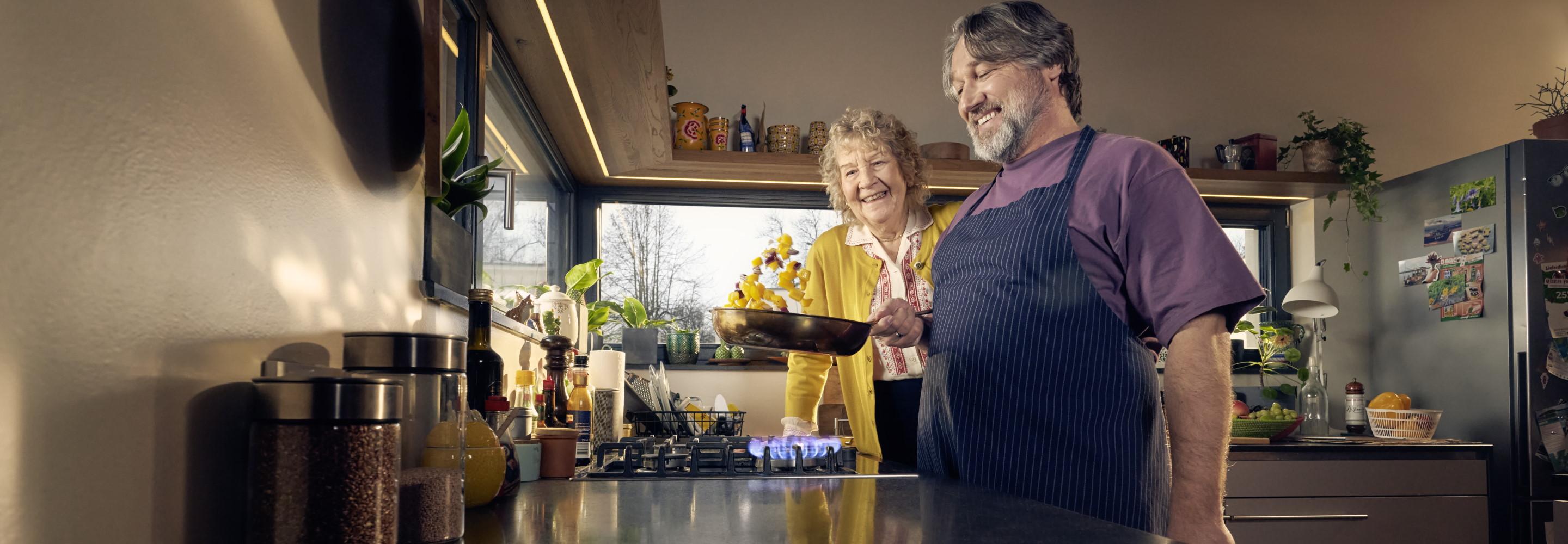Mann und ältere Dame kochen in einer Küche am Gasherd