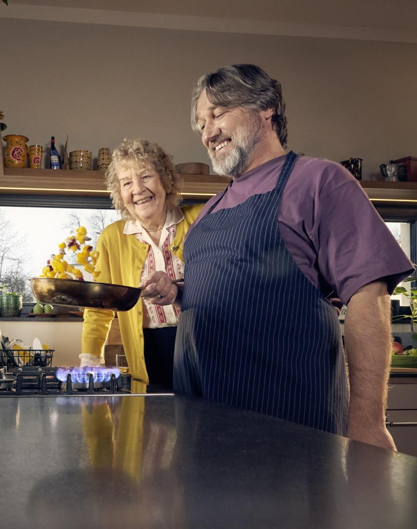 Mann und ältere Dame kochen in einer Küche am Gasherd