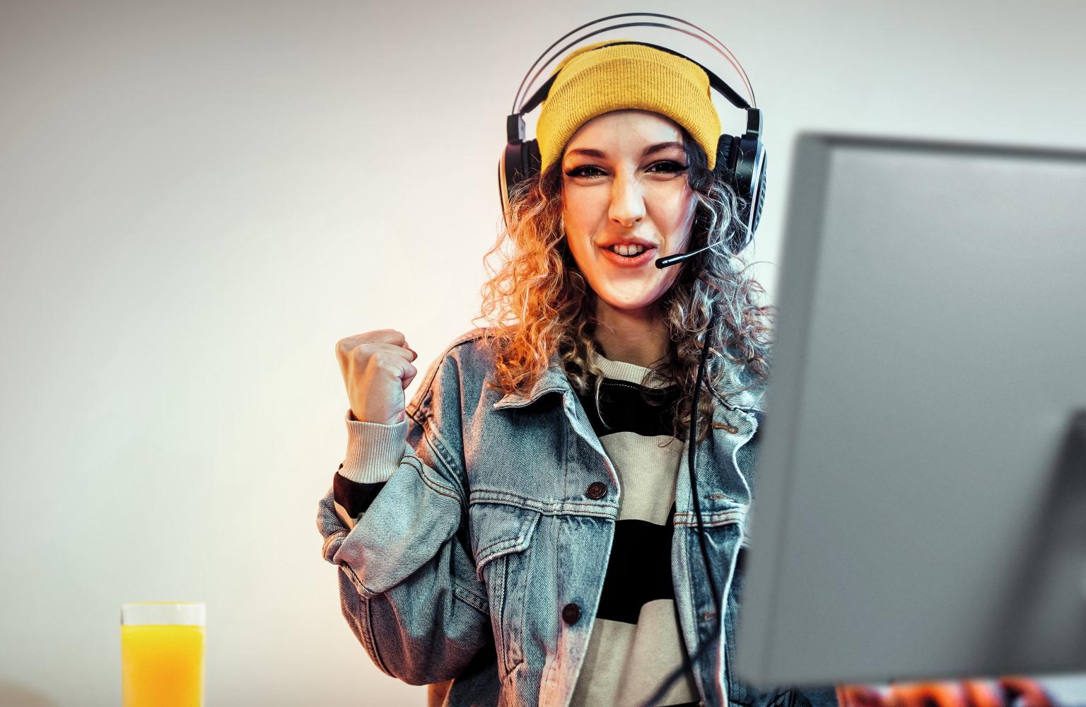 Junge Frau zockt am Laptop und ballt vor Freude die Faust