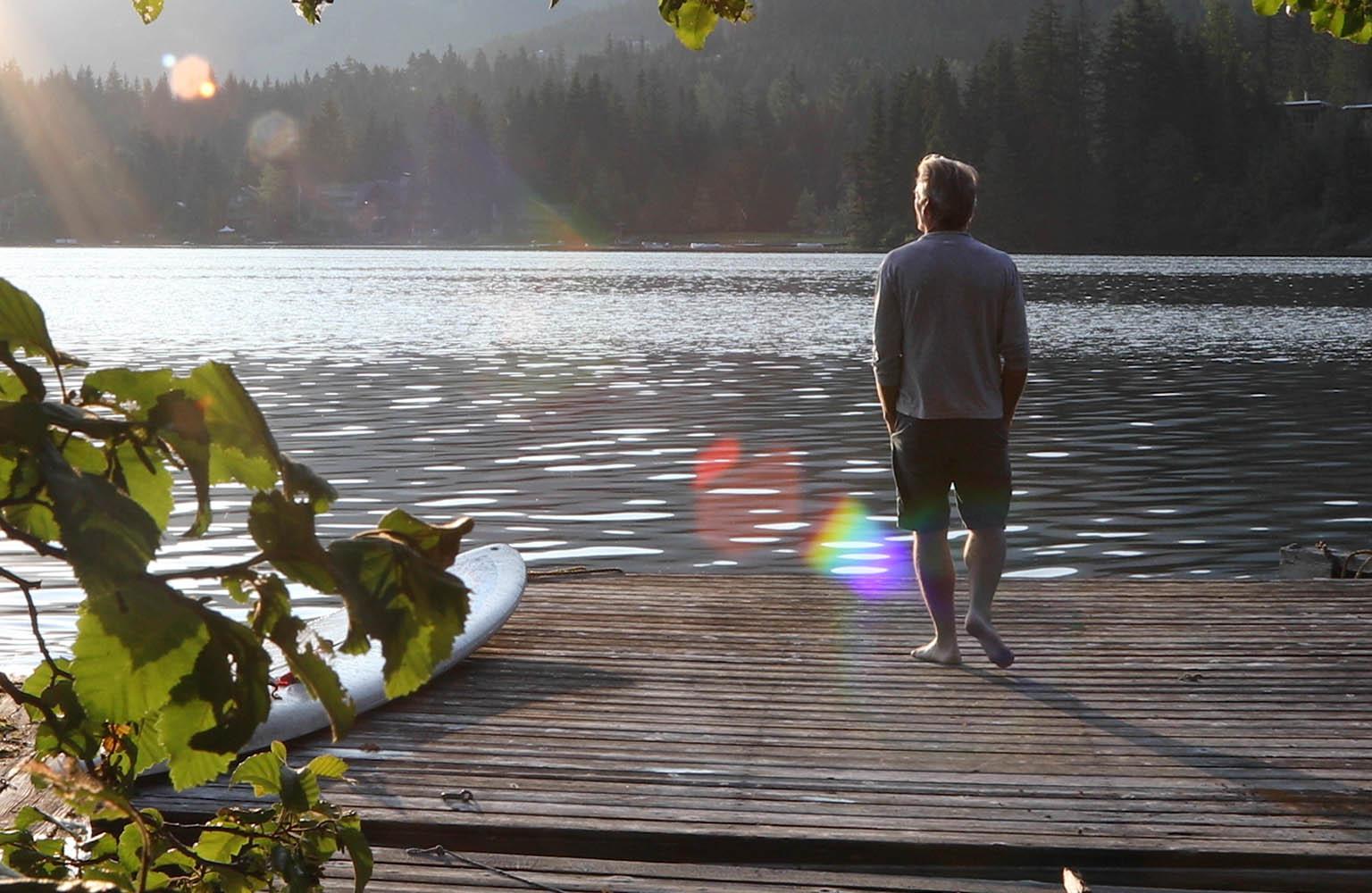 Mann blickt auf einem Steg auf einen See