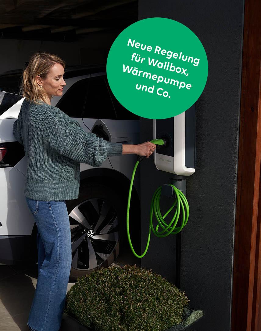 Frau steckt Kabel in eine Wallbox
