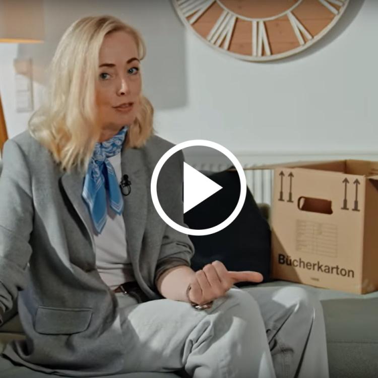 EWE-Smartgeberin Klaudia sitzt auf einer Couch neben einem Umzugskarton