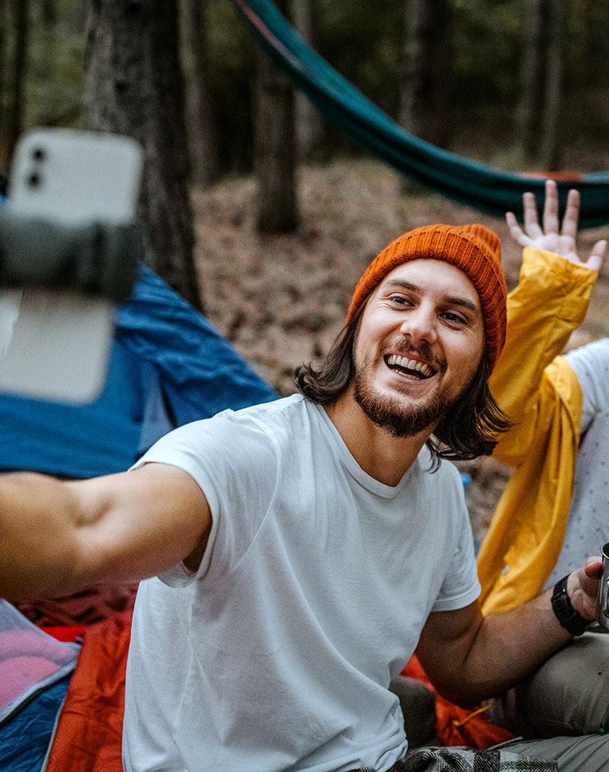 Mann und Frau fotografieren sich beim Campen mit Smartphone im Selfiestick