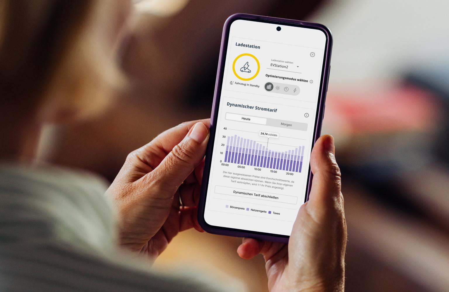 Eine Frau schaut sich auf dem Smartphone den EWE Energiemanager an
