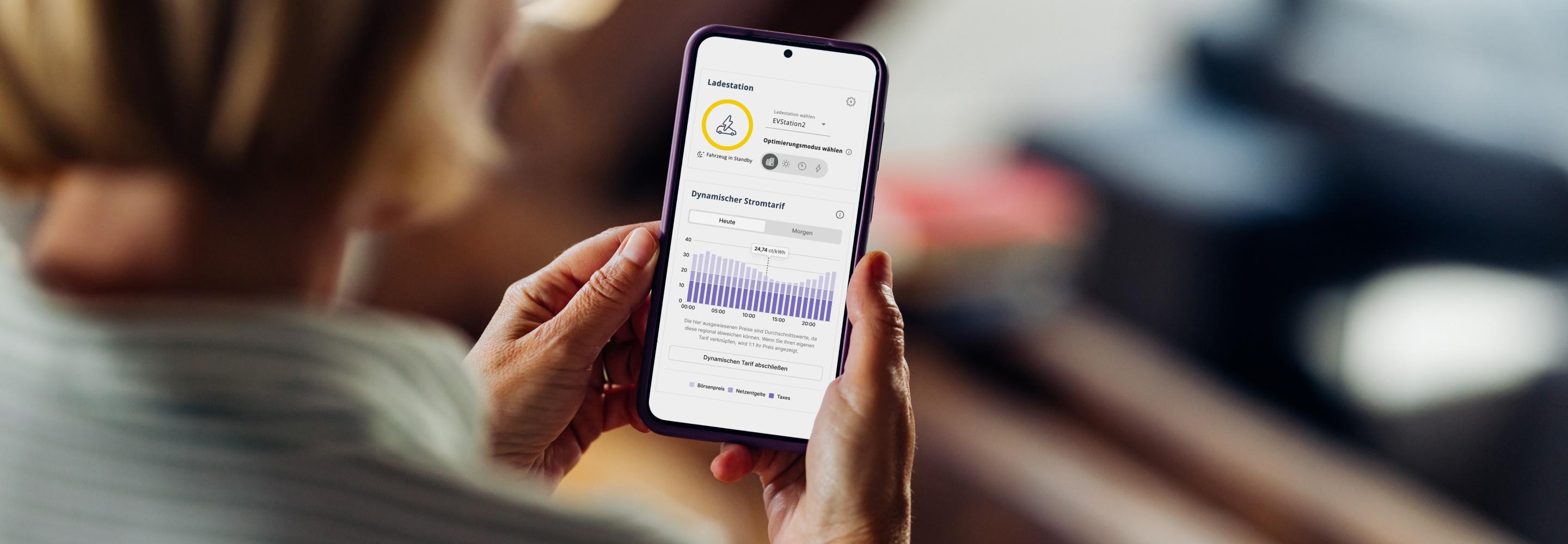 Eine Frau schaut sich auf dem Smartphone den EWE Energiemanager an