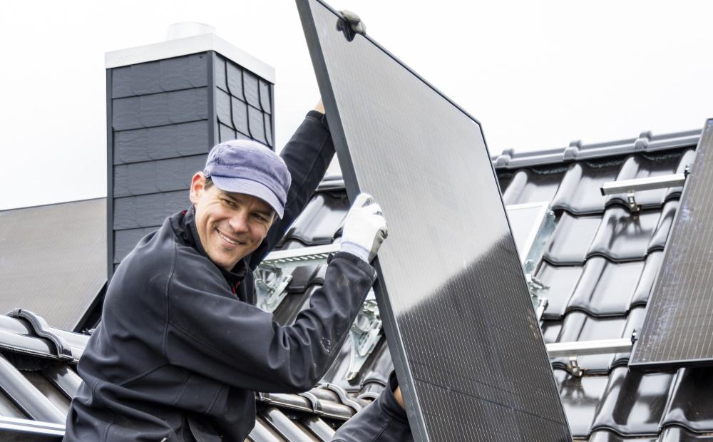 Fachhandwerker installiert Solarmodule auf einem Hausdach