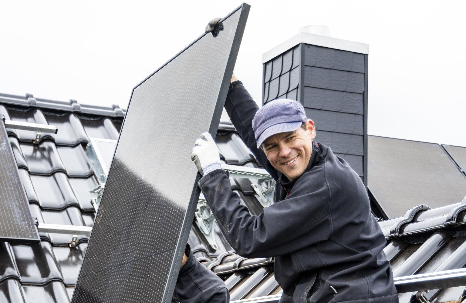 Fachhandwerker installiert Solarmodule auf einem Hausdach