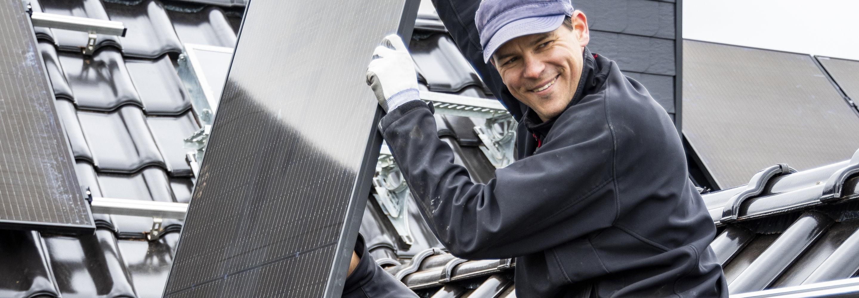 Fachhandwerker installiert Solarmodule auf einem Hausdach