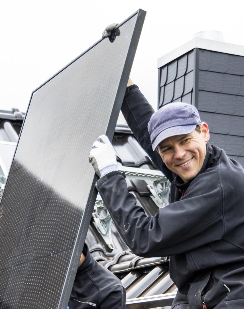 Fachhandwerker installiert Solarmodule auf einem Hausdach