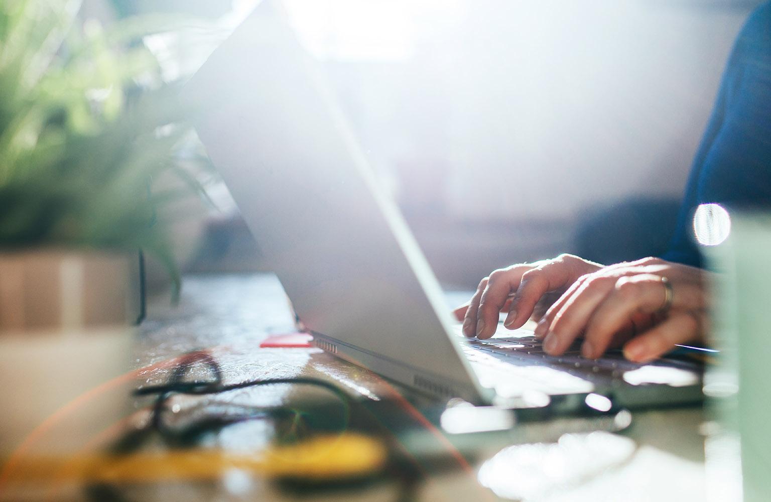 Zwei Hände tippen auf Laptop