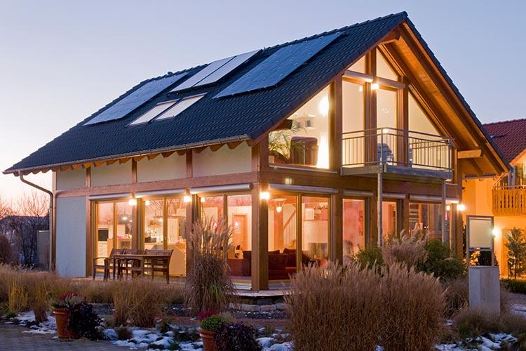 Beleuchtetes Haus mit PV-Anlage in der Dämmerung