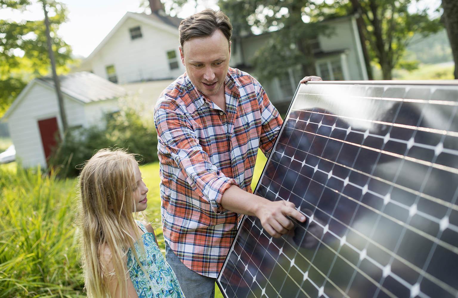 Vater zeigt seiner Tochter ein Solarmodul