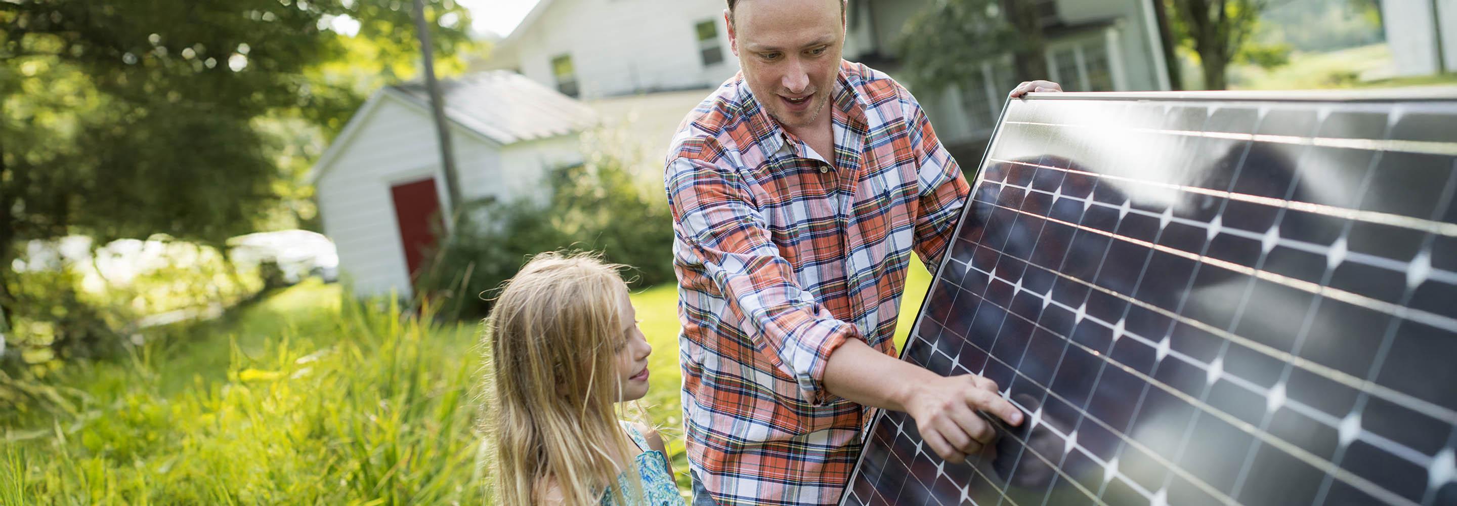 Vater zeigt seiner Tochter ein Solarmodul