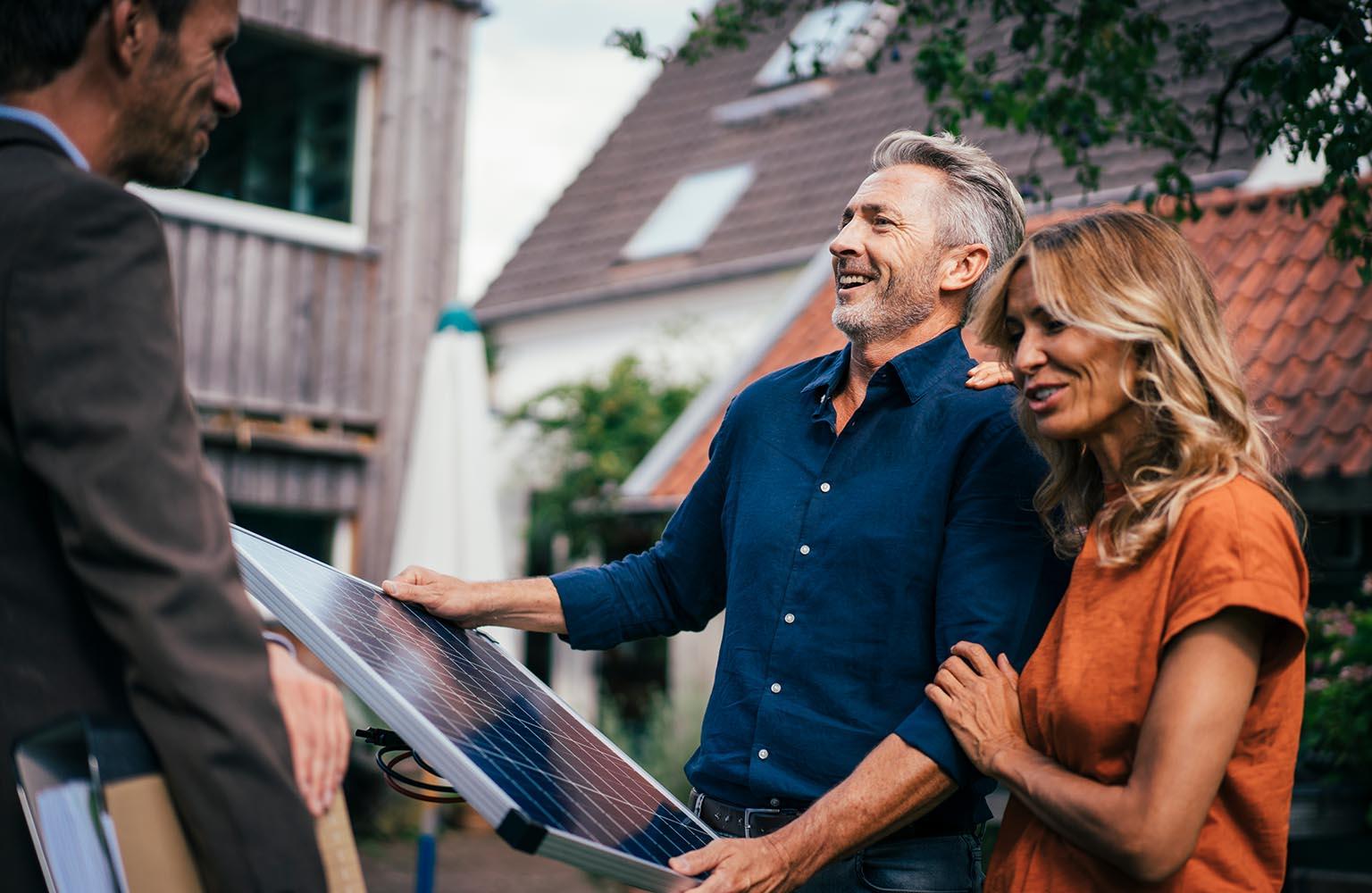 Vertreter übergibt Mann und Frau ein PV-Modul