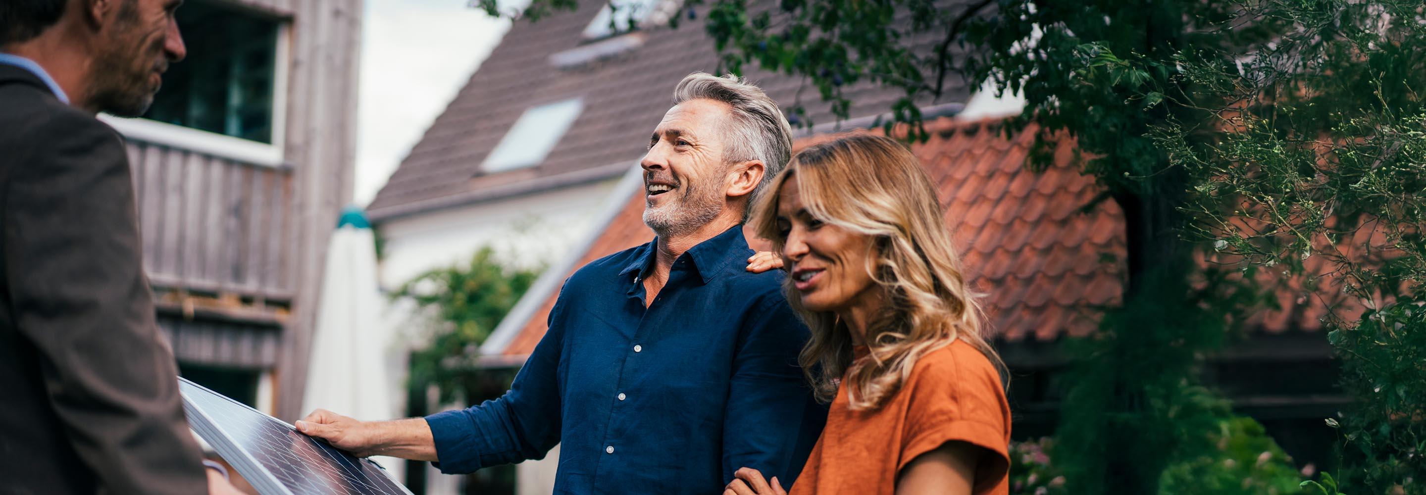 Vertreter übergibt Mann und Frau ein PV-Modul