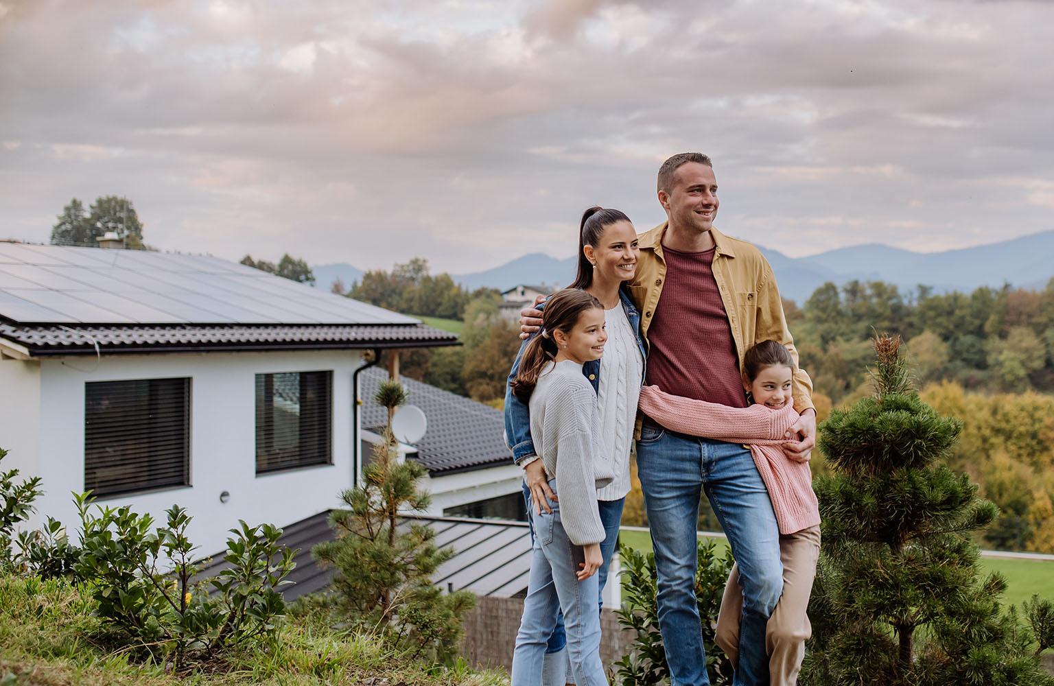 Familie steht vor einem Haus auf dem eine PV-Anlage angebracht ist