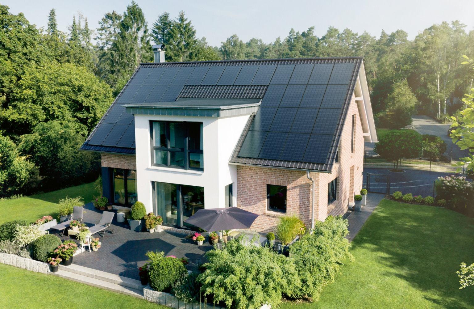 Haus mit Dach voller Solarmodule und einem hübschen Garten