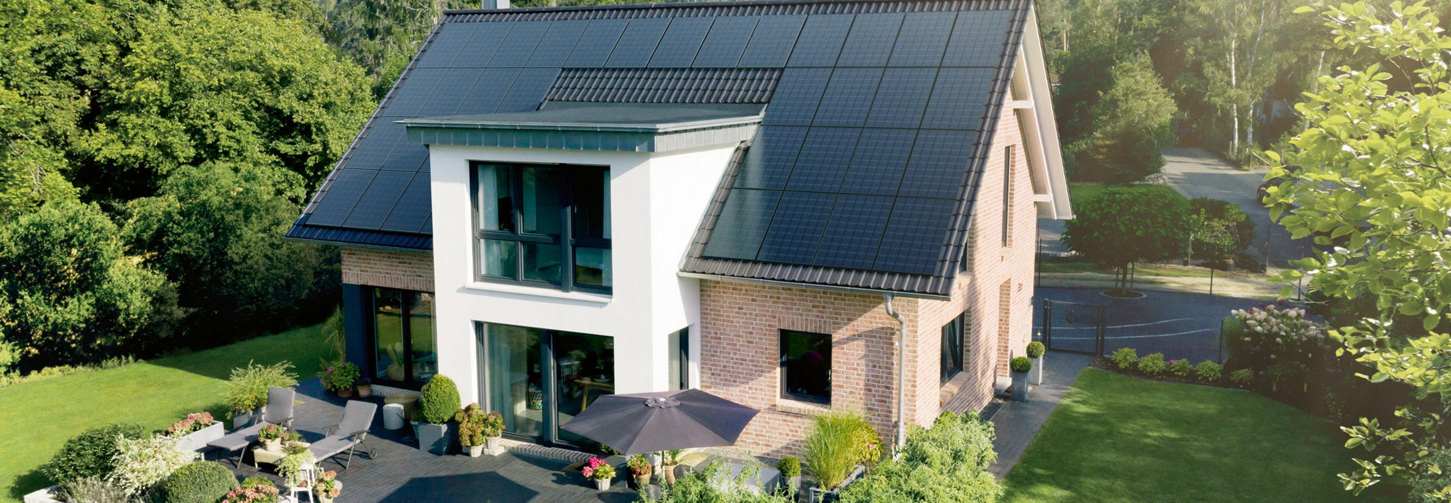 Haus mit Dach voller Solarmodule und einem hübschen Garten