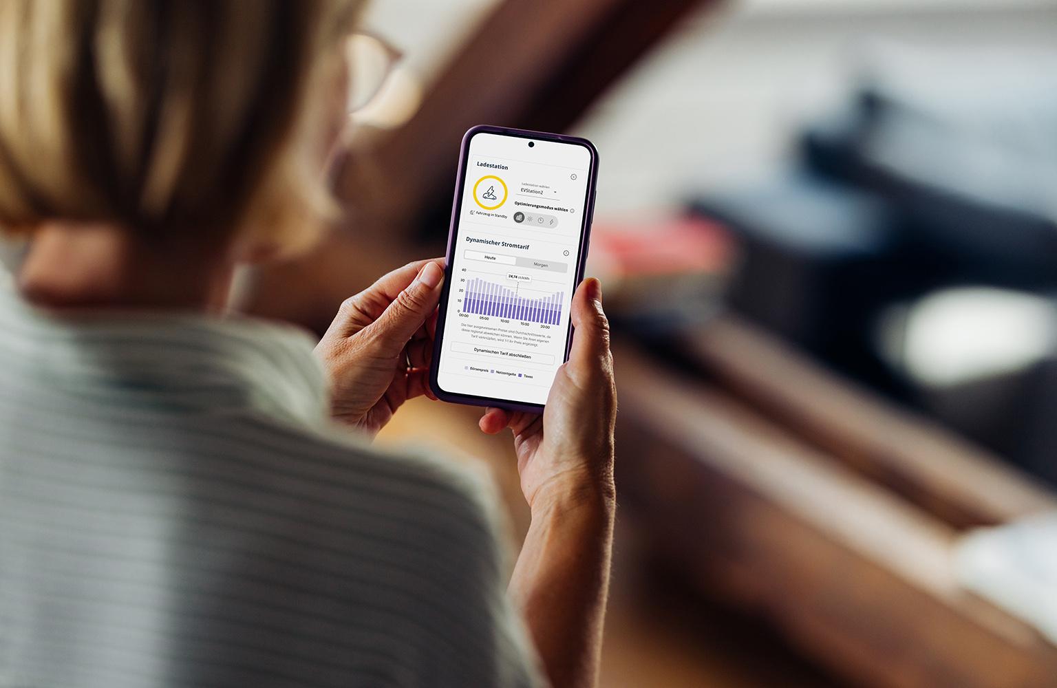Frau mit Smartphone auf dessen Bildschirm der EWE Energiemanager abgebildet ist