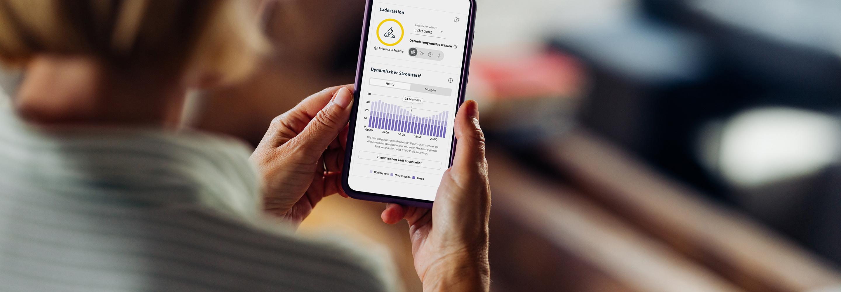 Frau mit Smartphone auf dessen Bildschirm der EWE Energiemanager abgebildet ist