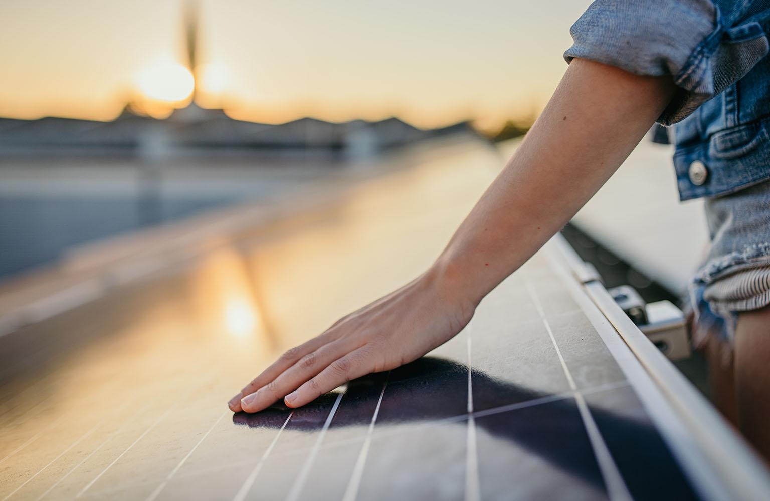 Hand streicht über PV-Modul