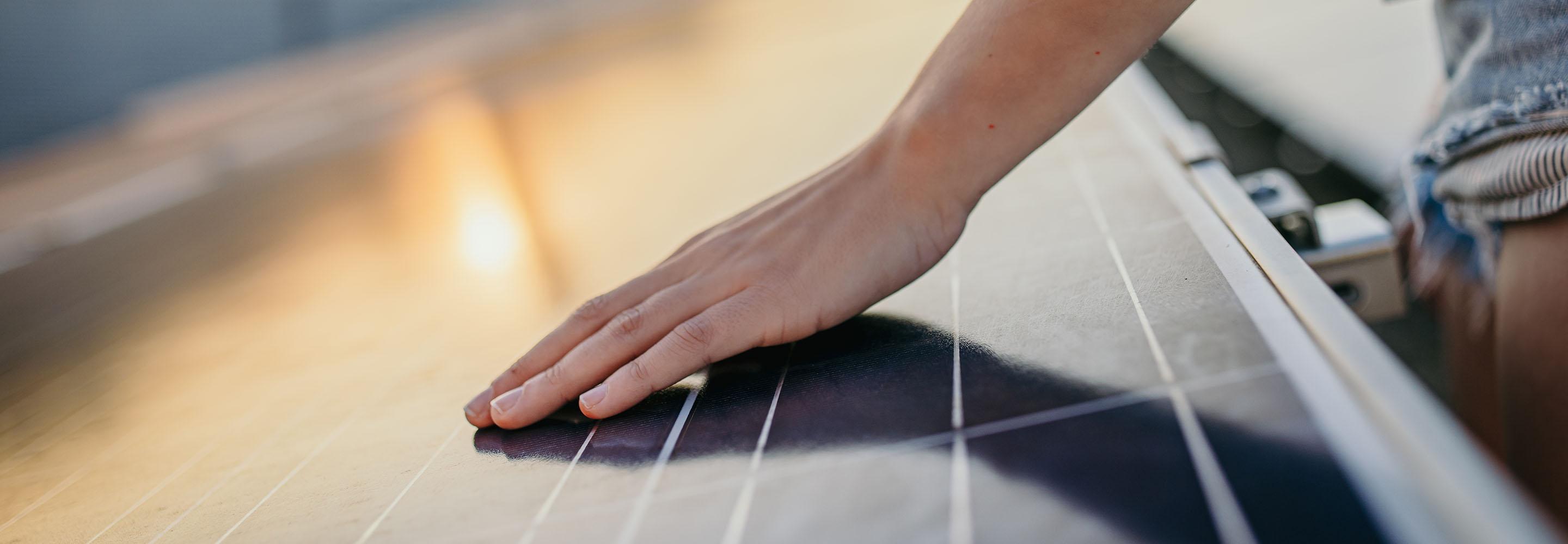 Hand streicht über PV-Modul
