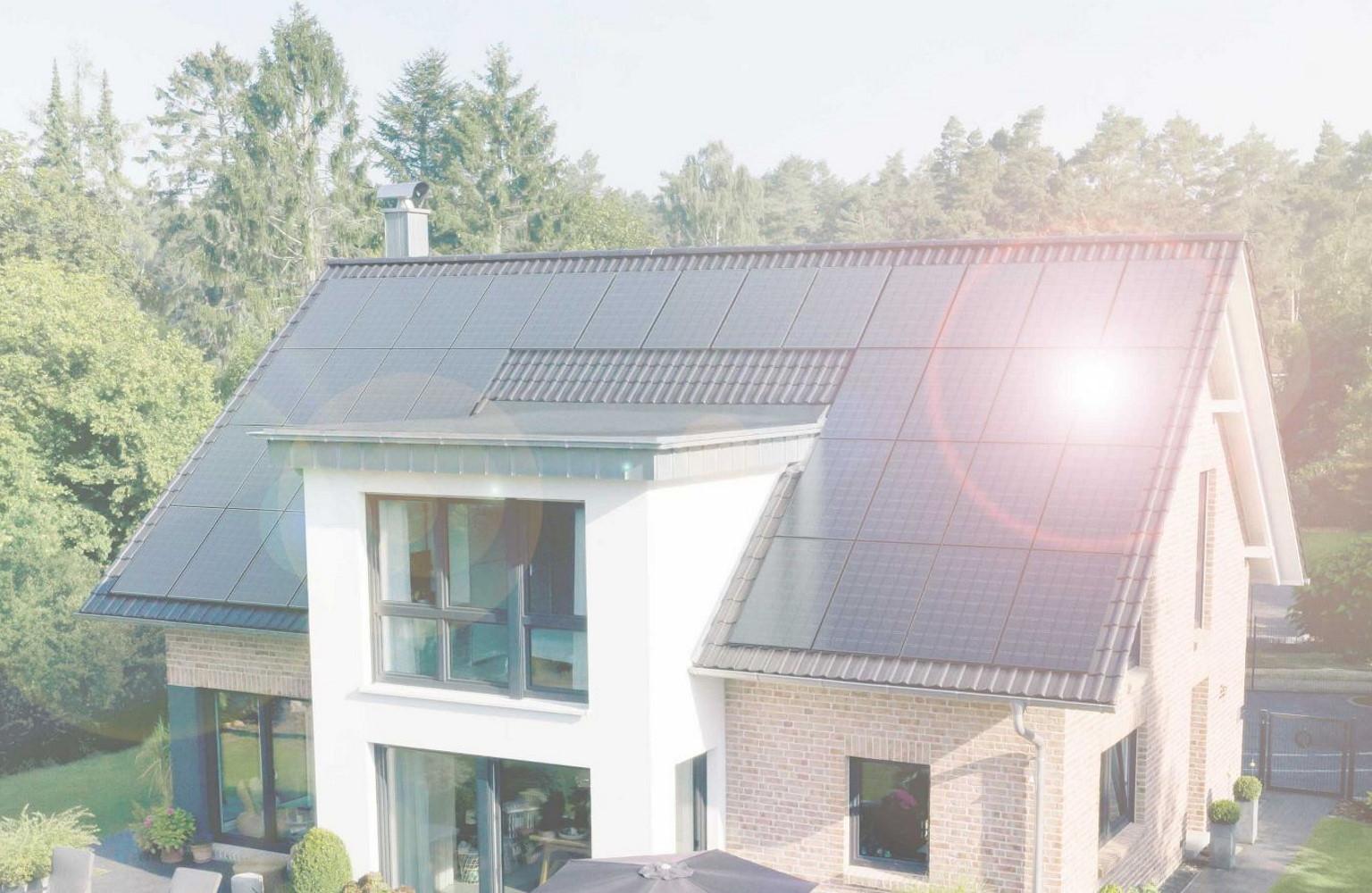 Haus mit Solarmodulen auf dem Dach, in denen Sonne reflektiert