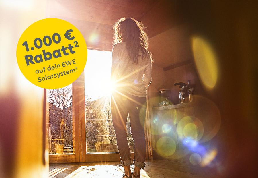 Frau steht vor der Wohnzimmertür, durch die die Sonne scheint