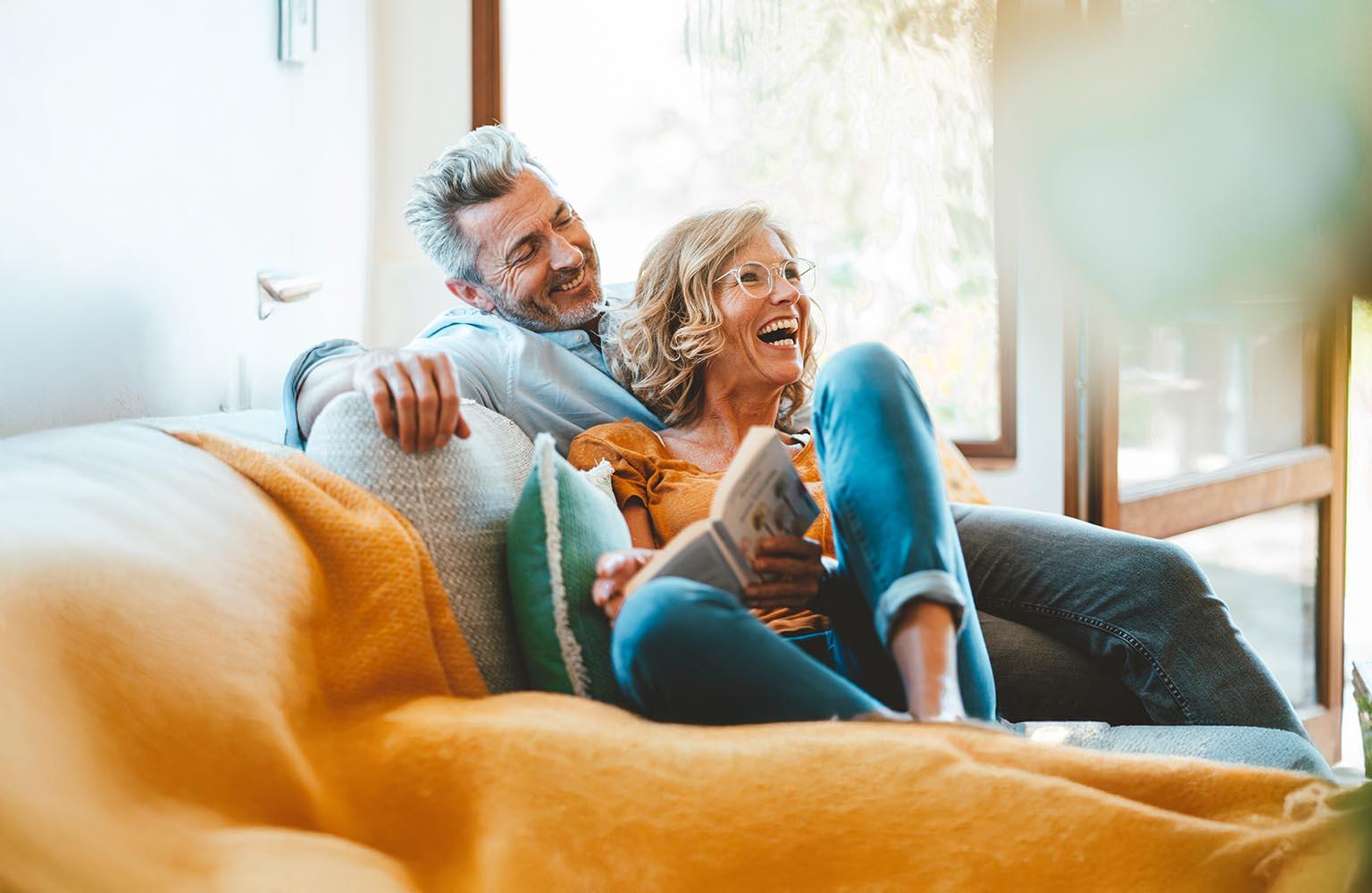 Pärchen auf dem Sofa mit Buch in der Hand freut sich