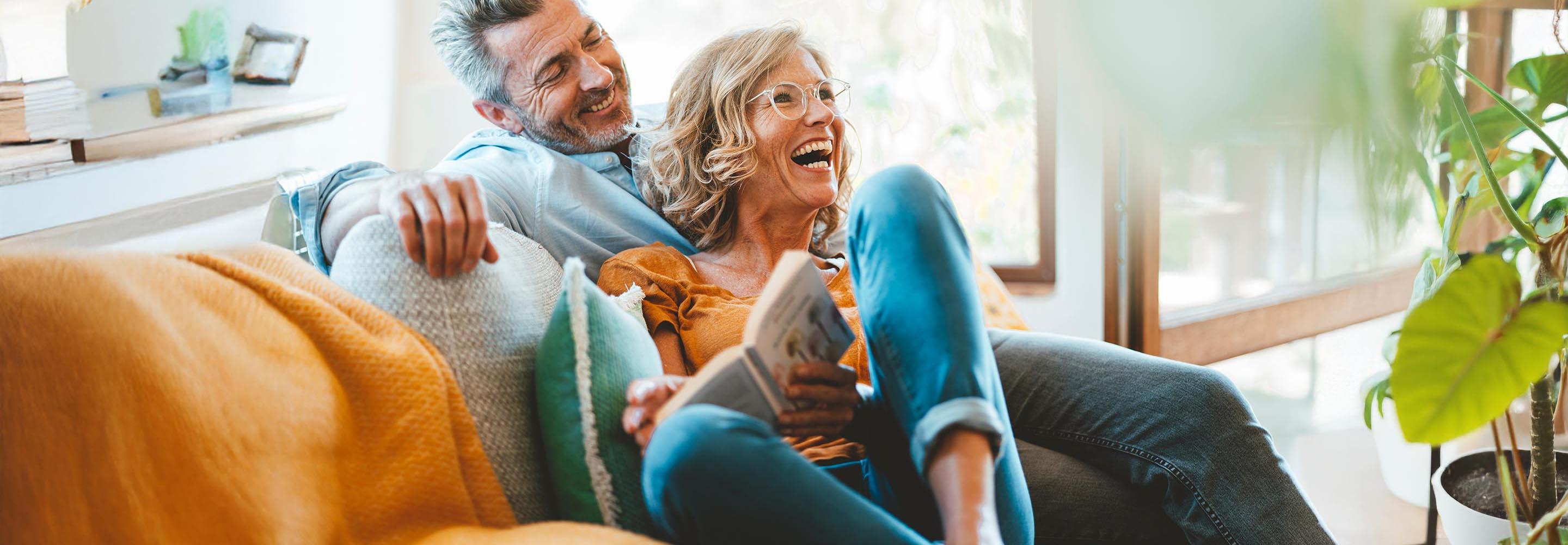 Pärchen auf dem Sofa mit Buch in der Hand freut sich