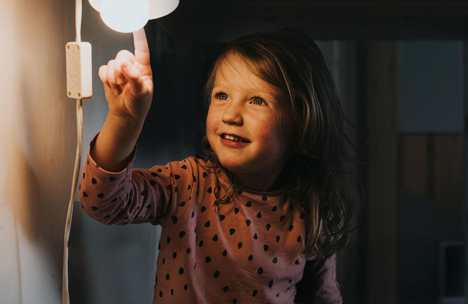 Mädchen zeigt auf angeschaltete Lampe