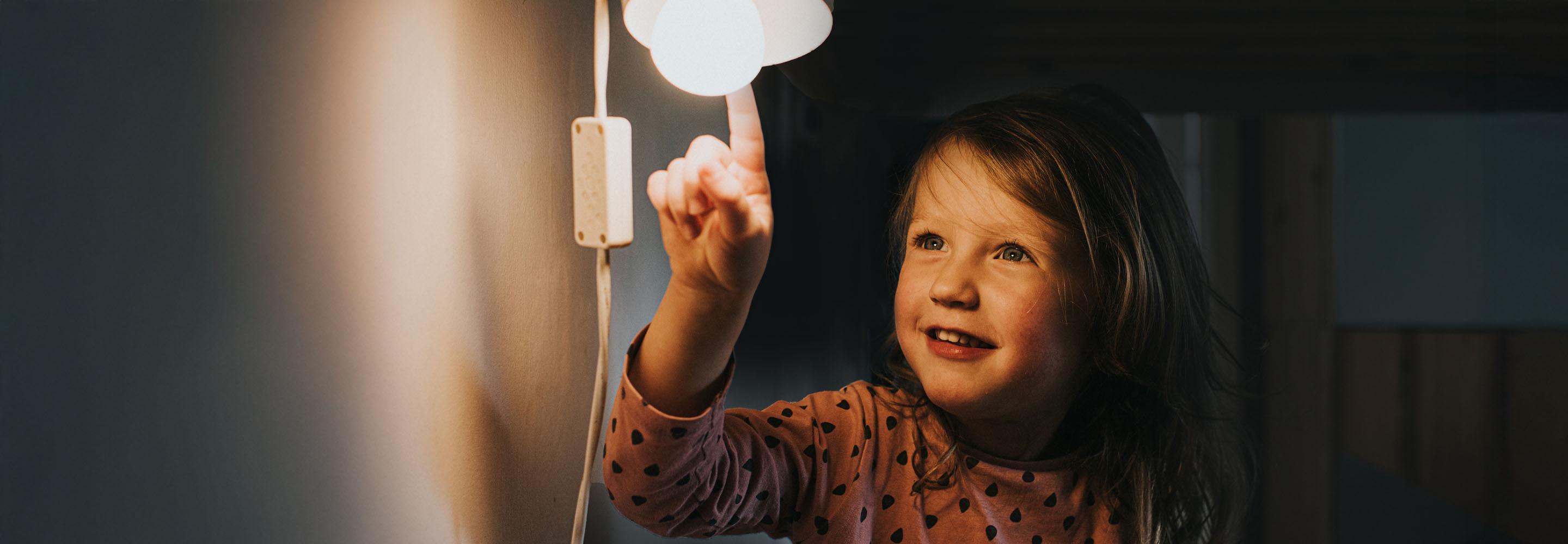 Mädchen zeigt auf angeschaltete Lampe