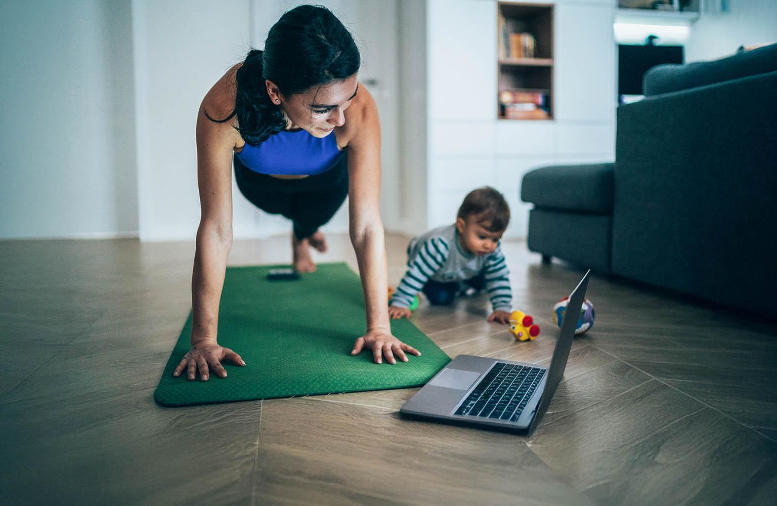 Mutter macht zuhause Sport, während ihr Baby neben ihr spielt