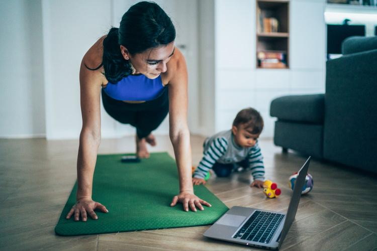 Mutter macht zuhause Sport, während ihr Baby neben ihr spielt