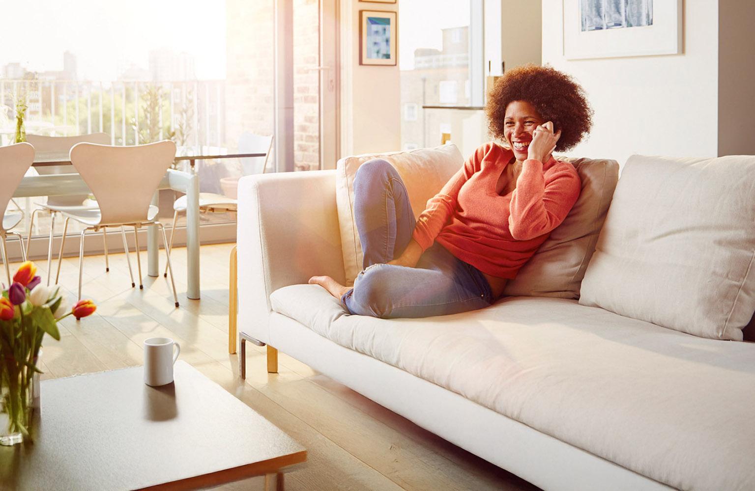 Frau telefoniert mit dem Smartphone auf dem Sofa