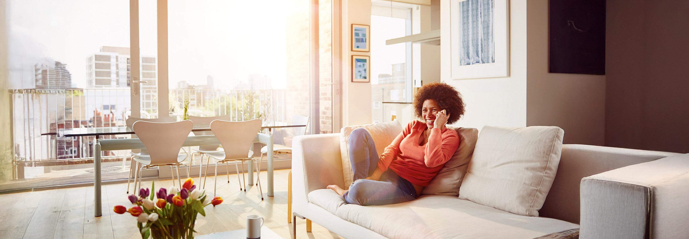 Frau telefoniert mit dem Smartphone auf dem Sofa