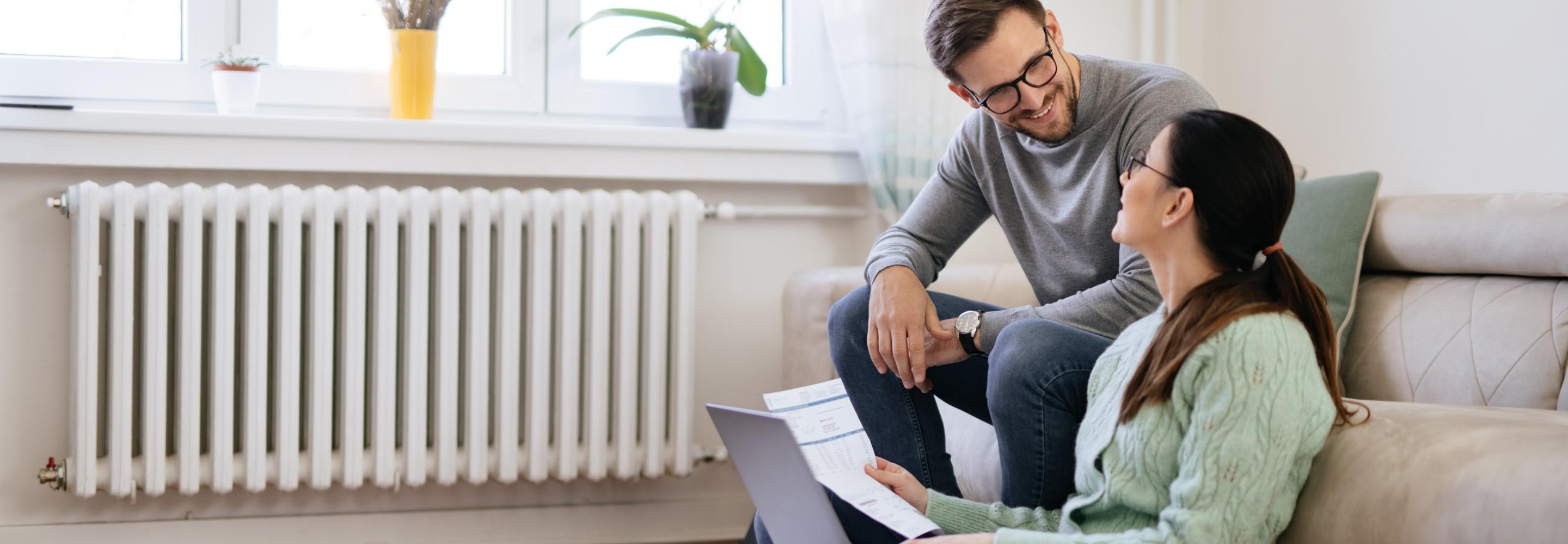 Junges Pärchen mit Zetteln und Laptop auf einer Couch
