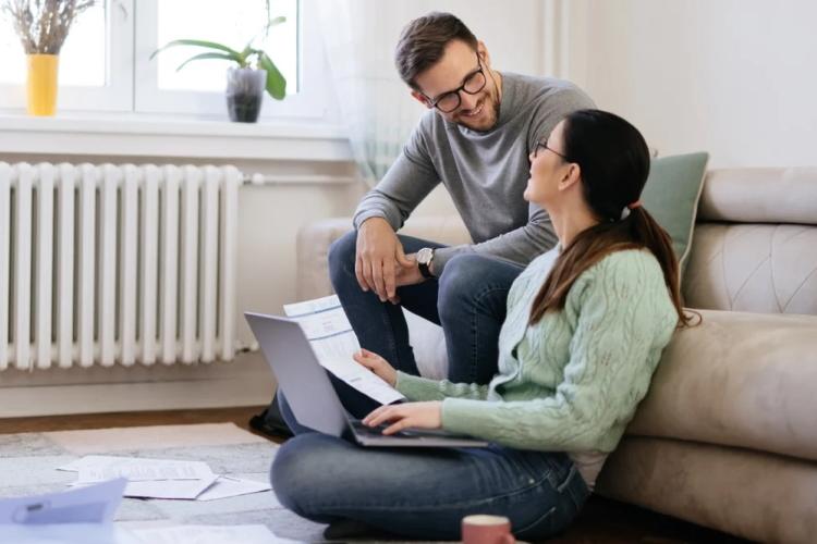 Junges Pärchen mit Zetteln und Laptop auf einer Couch