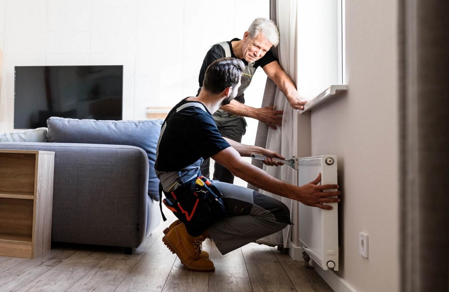 Zwei Handwerker installieren einen Heizkörper