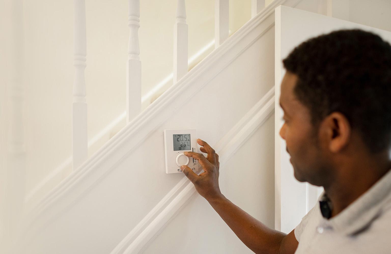 Mann stellt digitales Thermostat an einer Treppe ein