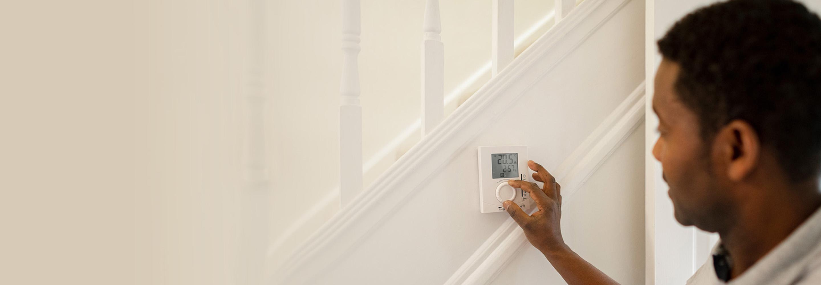 Mann stellt digitales Thermostat an einer Treppe ein