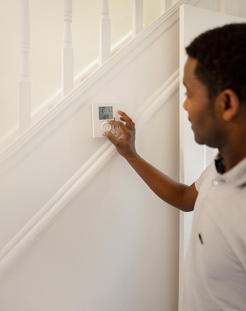 Mann stellt digitales Thermostat an einer Treppe ein