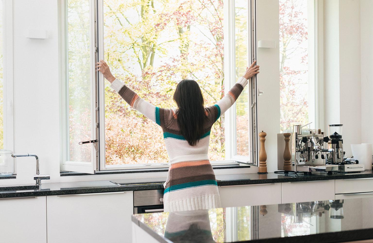 Frau öffnet die Fenster in der Küche