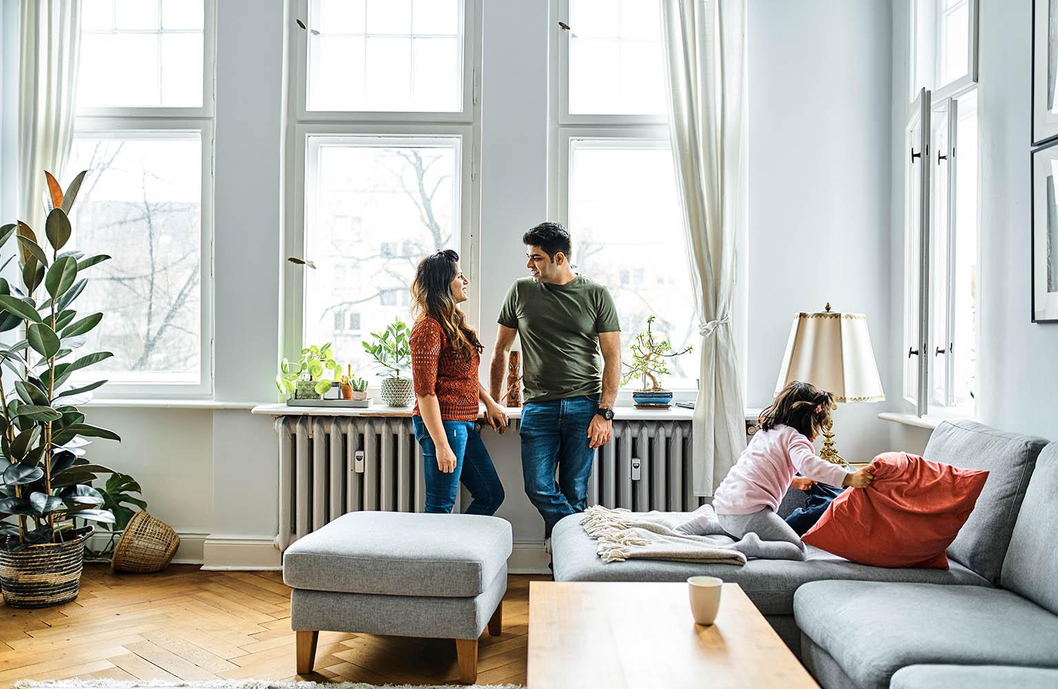 Pärchen lehnt an der Fensterbank an einer Heizung im Wohnzimmer