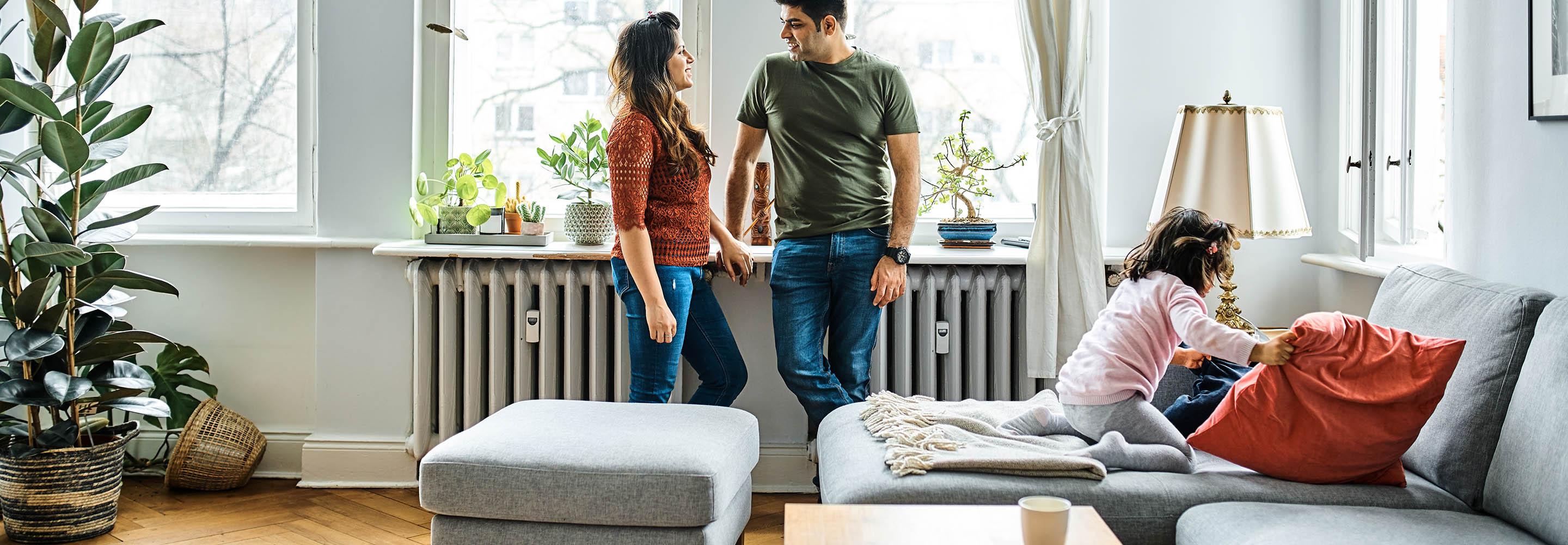Pärchen lehnt an der Fensterbank an einer Heizung im Wohnzimmer
