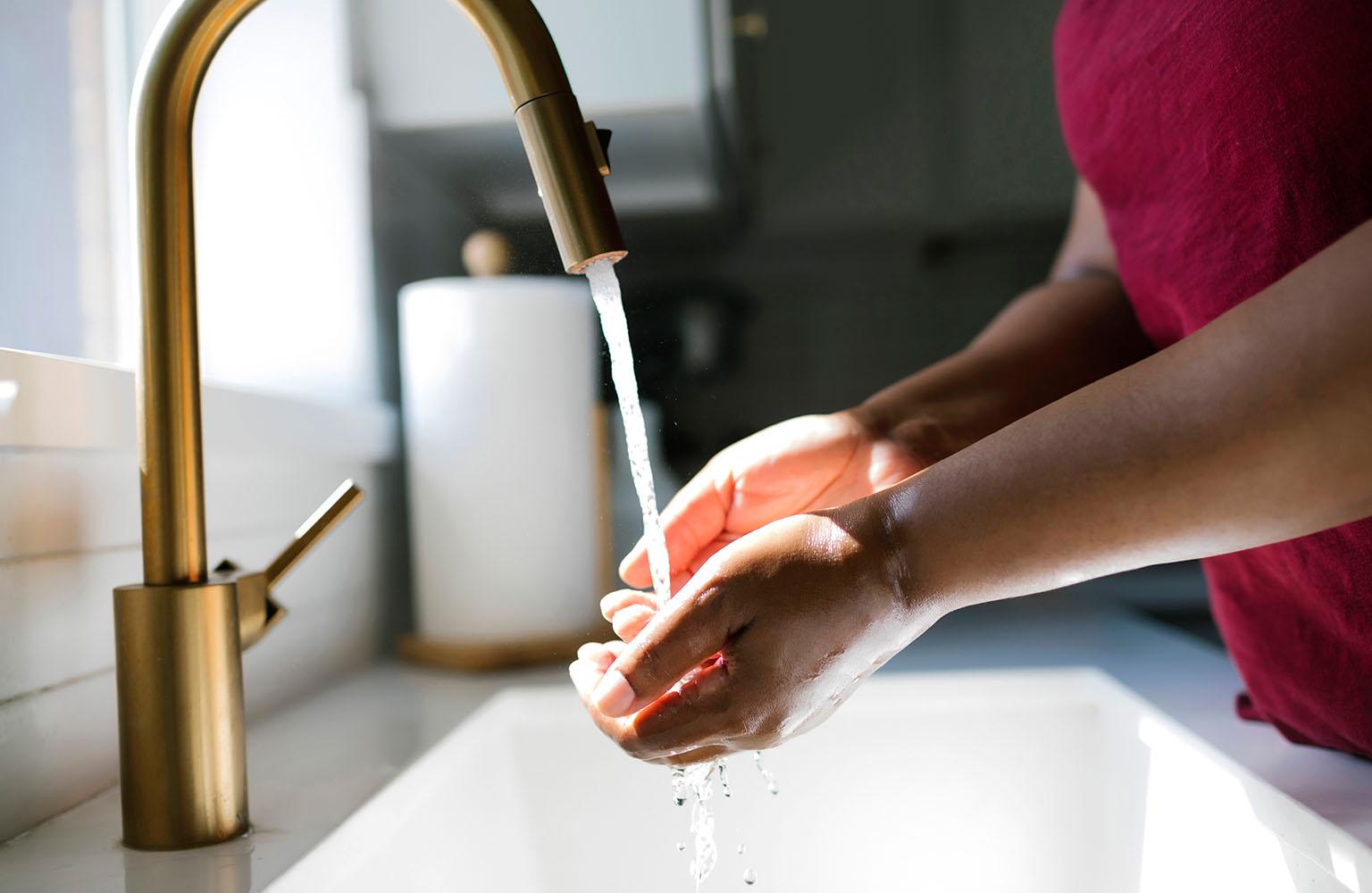 Zwei Hände unter dem Strahl eines Wasserhahns