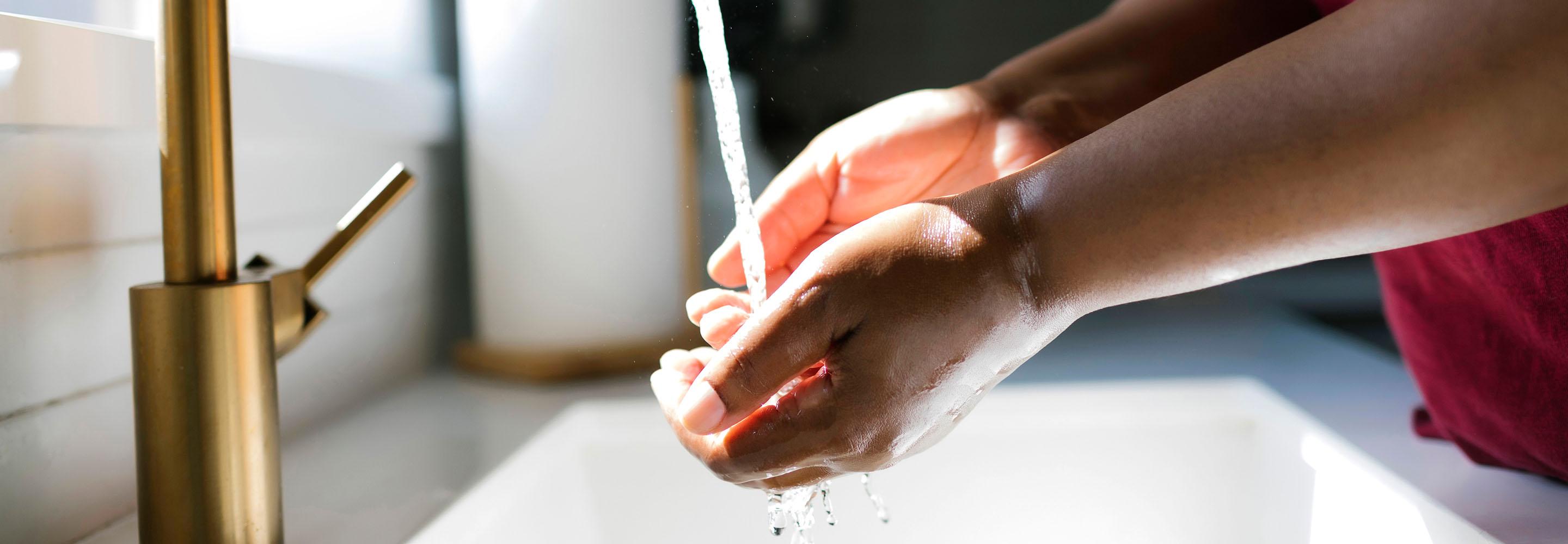 Zwei Hände unter dem Strahl eines Wasserhahns