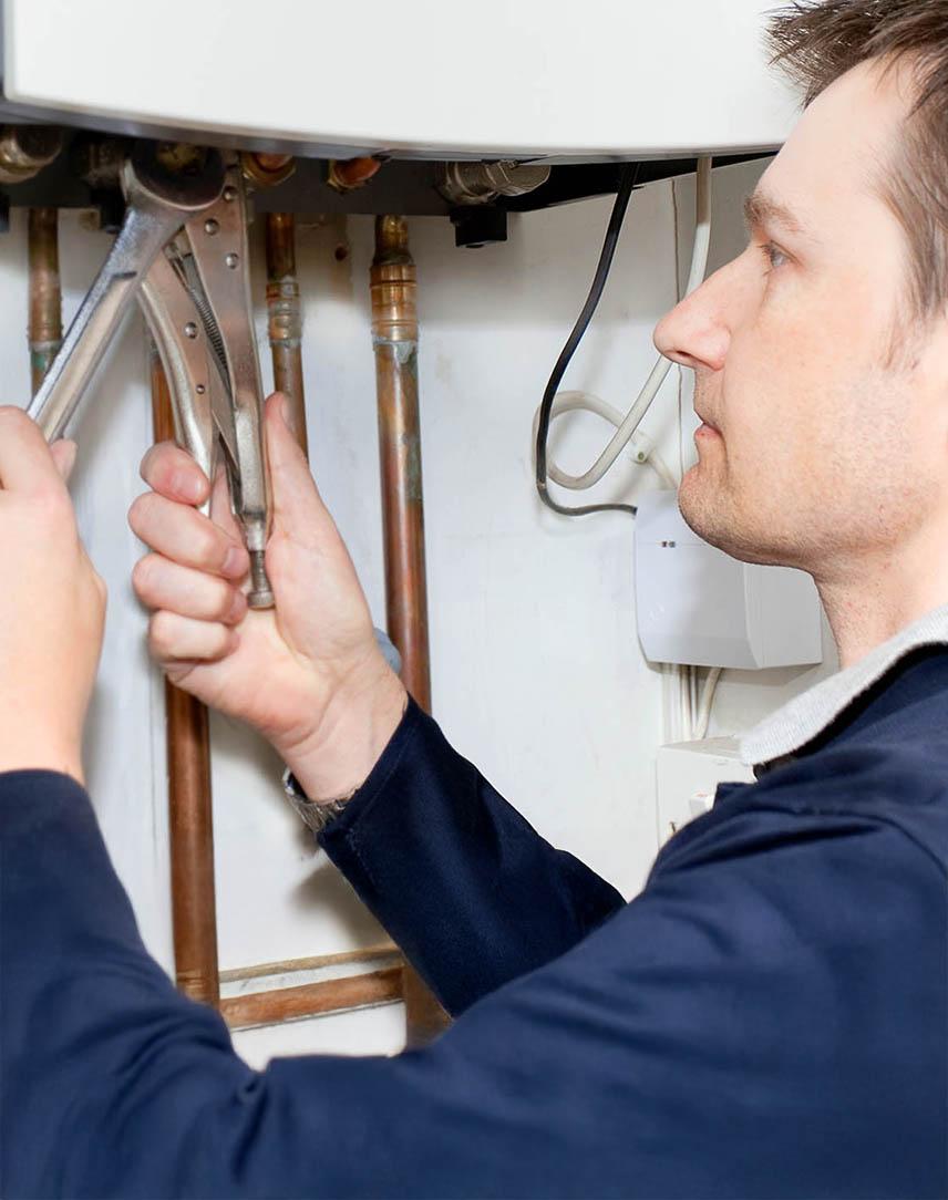 Mann arbeitet mit einer Zange an der Heizungsanlage