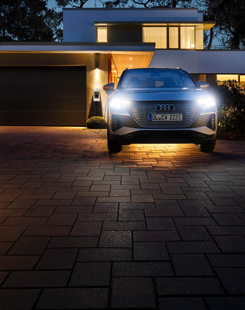 Auto vor einem Haus mit Wallbox im Hintergrund.